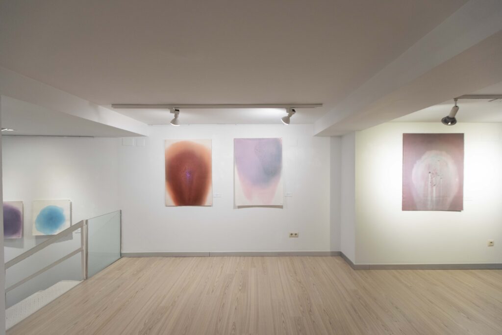 Artist Nuria Vidal standing in front of her luminous abstract paintings at Alba Cabrera gallery during Abierto Valencia 2025.