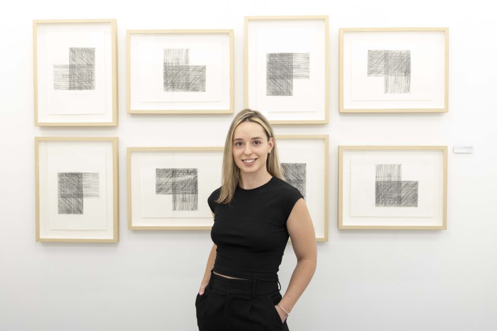 Estefanía Serrano Soriano posant à côté d’une œuvre photographique abstraite dans la galerie Cuatro pendant Abierto Valencia 2025.