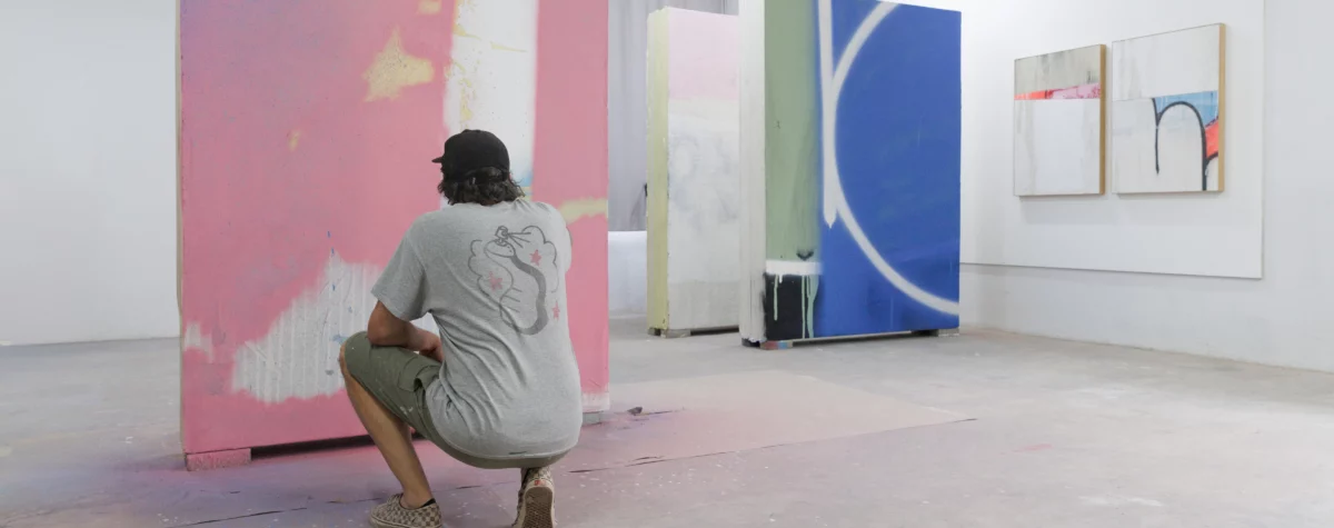 L’artiste Tilt en résidence à Jardin Rouge, Marrakech (2025), peignant un grand panneau abstrait rose, bleu et noir pour l’exposition Waiting for Barbarians à la Fondation Montresso*. magazine art mag