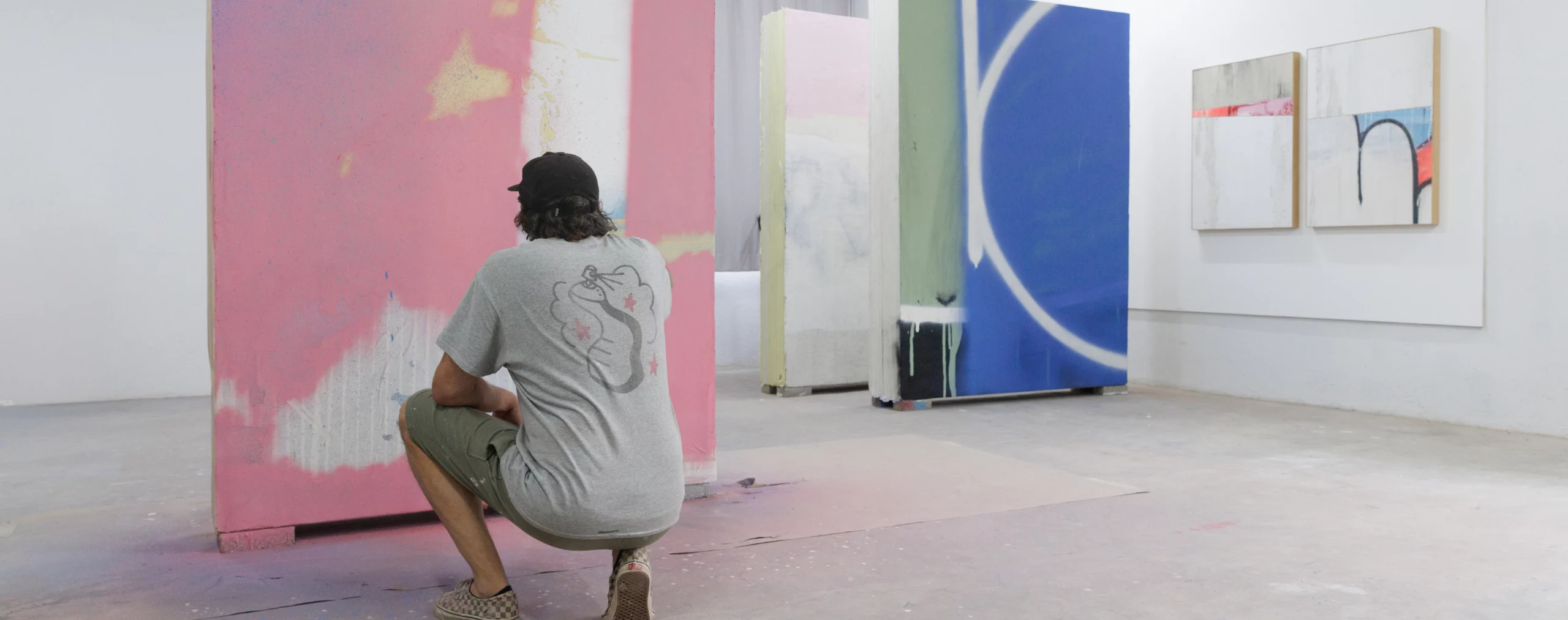 L’artiste Tilt en résidence à Jardin Rouge, Marrakech (2025), peignant un grand panneau abstrait rose, bleu et noir pour l’exposition Waiting for Barbarians à la Fondation Montresso*. magazine art mag