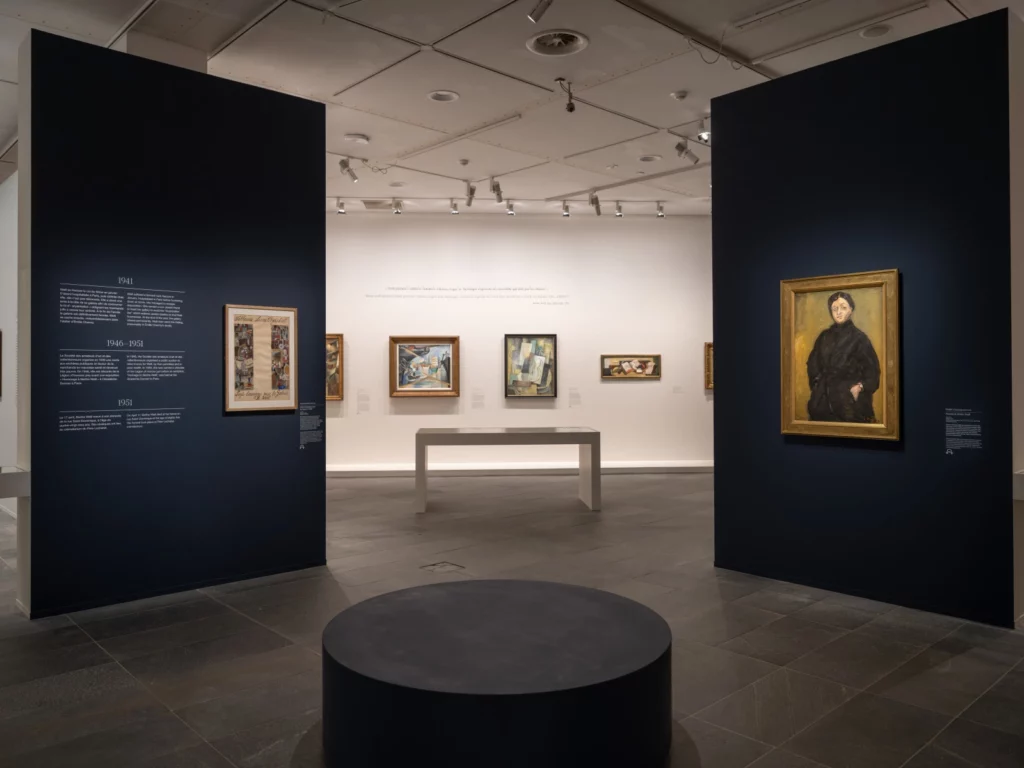 Vue de salle au ton bleu nuit présentant les œuvres majeures des artistes de la galerie Berthe Weill, exposition « Galeriste d’avant-garde » au Musée de l’Orangerie.  Magazine Art mag
