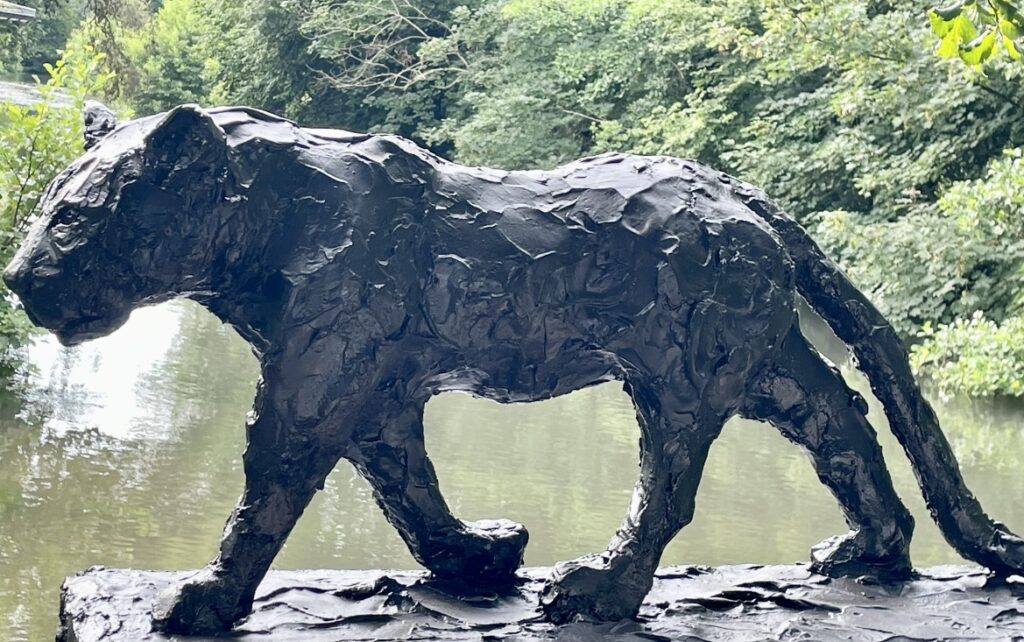 Animal sculpture in smoked ceramic by Régis Sinoquet — black panther, raw texture, natural background.