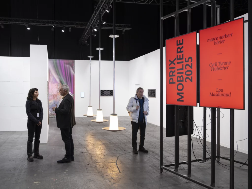 Installation du Prix Mobilière 2025 à Art Genève : visiteurs devant les écrans rouges annonçant les artistes nommés, dans un espace d’exposition contemporain à Palexpo.