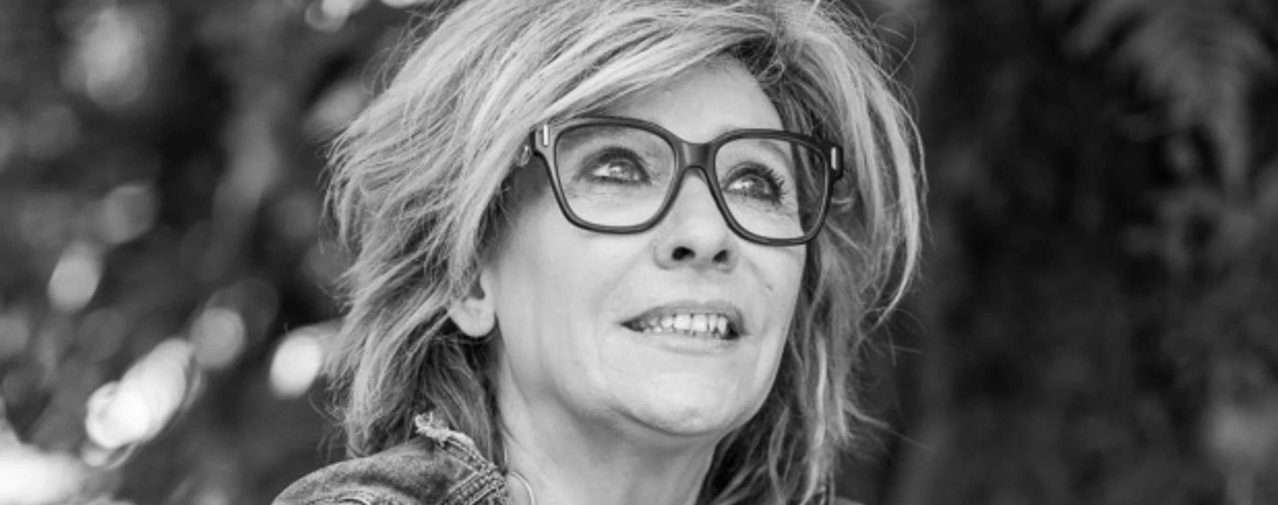 Portrait en noir et blanc de l’artiste contemporaine Flo Muliardo, regard tourné vers la lumière. Photographie illustrant son engagement auprès des enfants et la série Les Enfants Rois, présentée dans ART MAG.