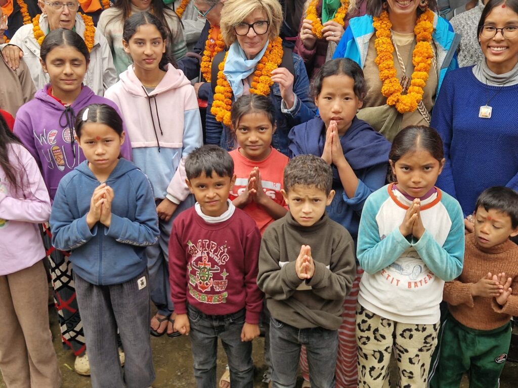 Flo Muliardo surrounded by children in Nepal during a visit with the association Les Enfants de Manasté. Photograph illustrating her human and artistic commitment for the series The Child Kings, featured in ART MAG.