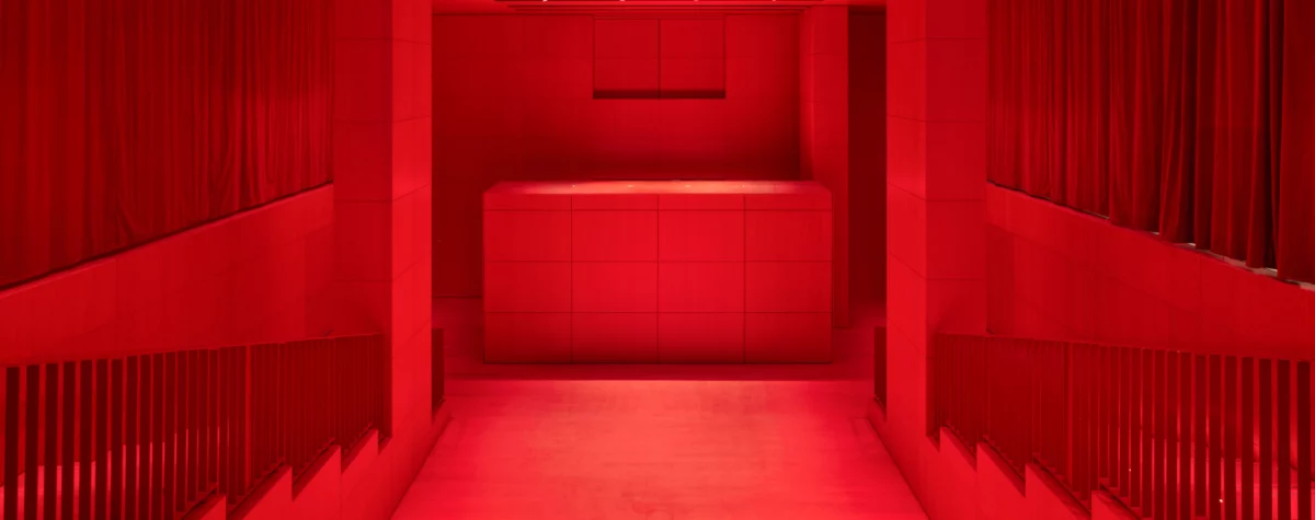 Intérieur du Studio Marie-Claude Beaud au Palais-Royal, auditorium de 110 places du nouveau bâtiment de la Fondation Cartier conçu par Jean Nouvel, baigné d’une lumière rouge immersive et dédié aux arts vivants, projections et rencontres.