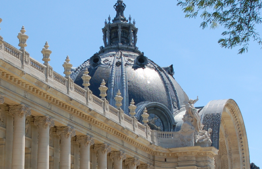 Facade of the Petit Palais in Paris, with its monumental columns and ornate dome, under a blue sky.