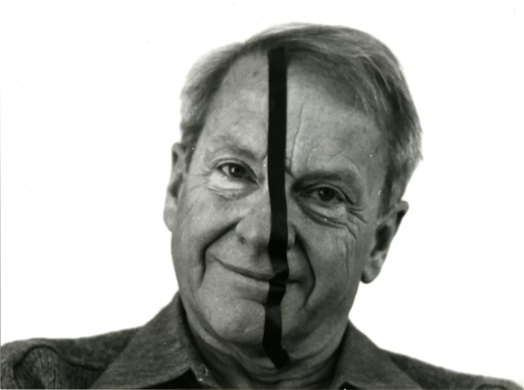 Portrait en noir et blanc de François Morellet avec une bande noire verticale sur le visage, évoquant son travail sur la géométrie, la règle et le hasard.
