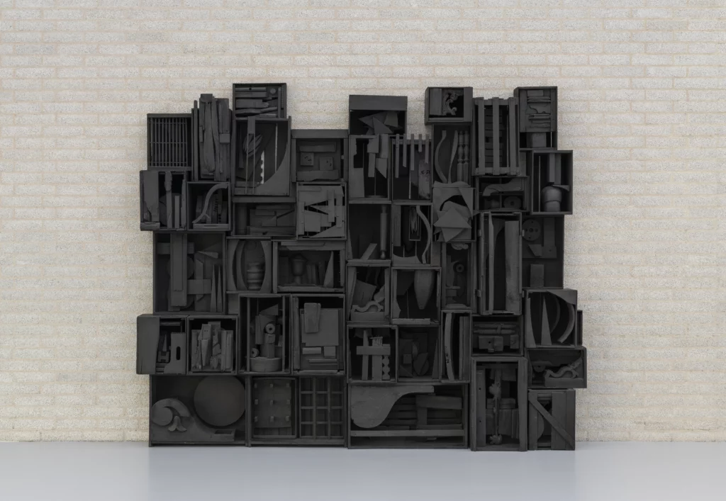 Assemblage mural en bois peint en noir de l’artiste Louise Nevelson, composé de boîtes et de formes sculptées, présenté au Centre Pompidou-Metz dans le cadre d’une exposition consacrée à la sculpture immersive du XXe siècle.