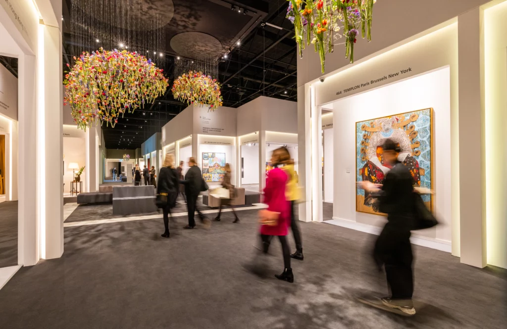 Hallway at TEFAF Maastricht 2026 with visitors, international gallery booths, and the fair’s signature hanging floral installations. Magazine Art Mag
