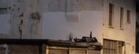 Pochoir de Banksy à Londres représentant deux enfants allongés sur un toit, l’un pointant le ciel, sur un mur urbain délabré.