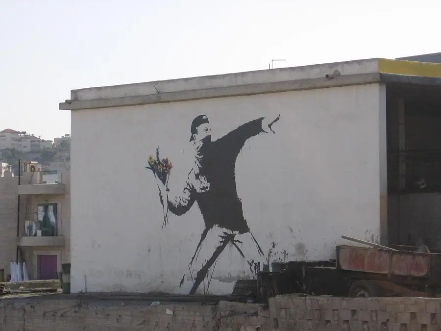 Avec Flower Thrower, Banksy détourne l'image de la violence en remplaçant une arme par un bouquet de fleurs.