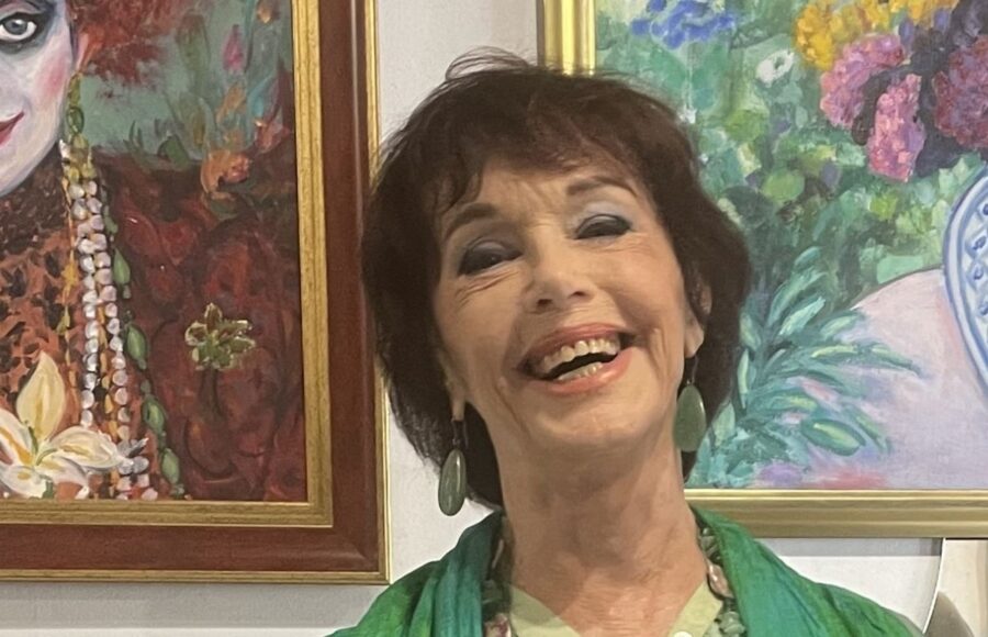 Anny Duperey peintre devant ses tableaux lors d'une exposition, une œuvre où la couleur et la lumière occupent une place centrale.